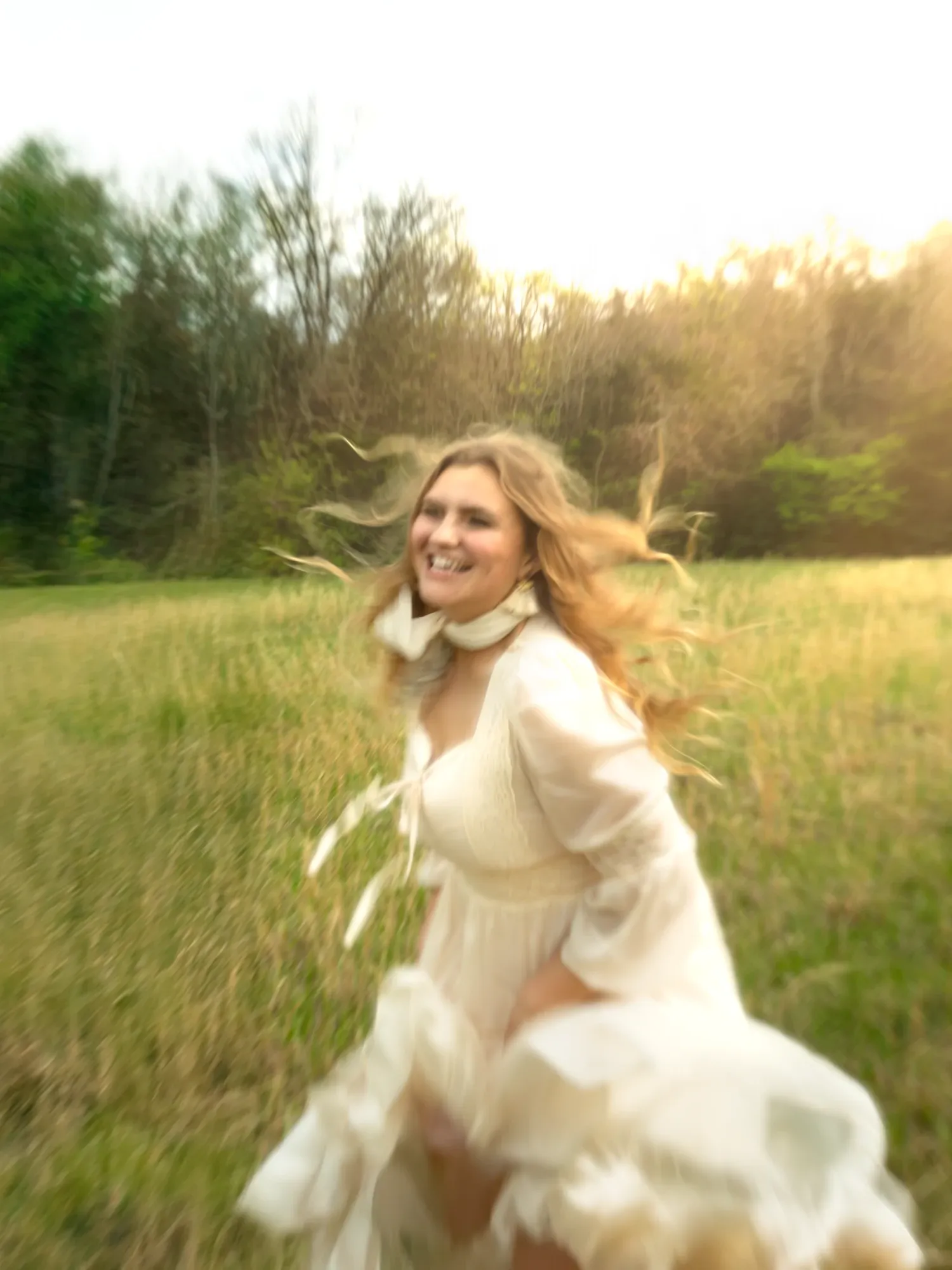 Nancy Ann running through a green field in a white dress