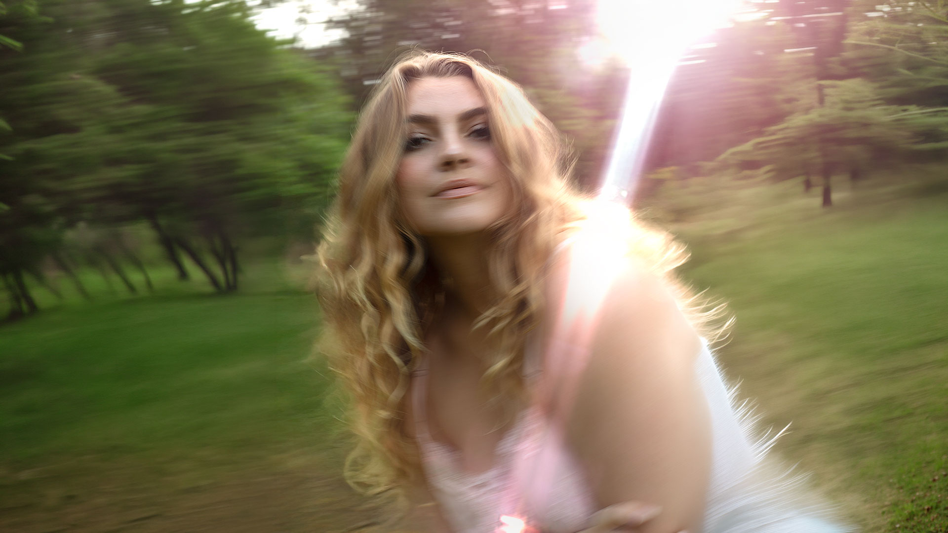 Nancy Ann in a sunlit wood, a lens flare across the frame