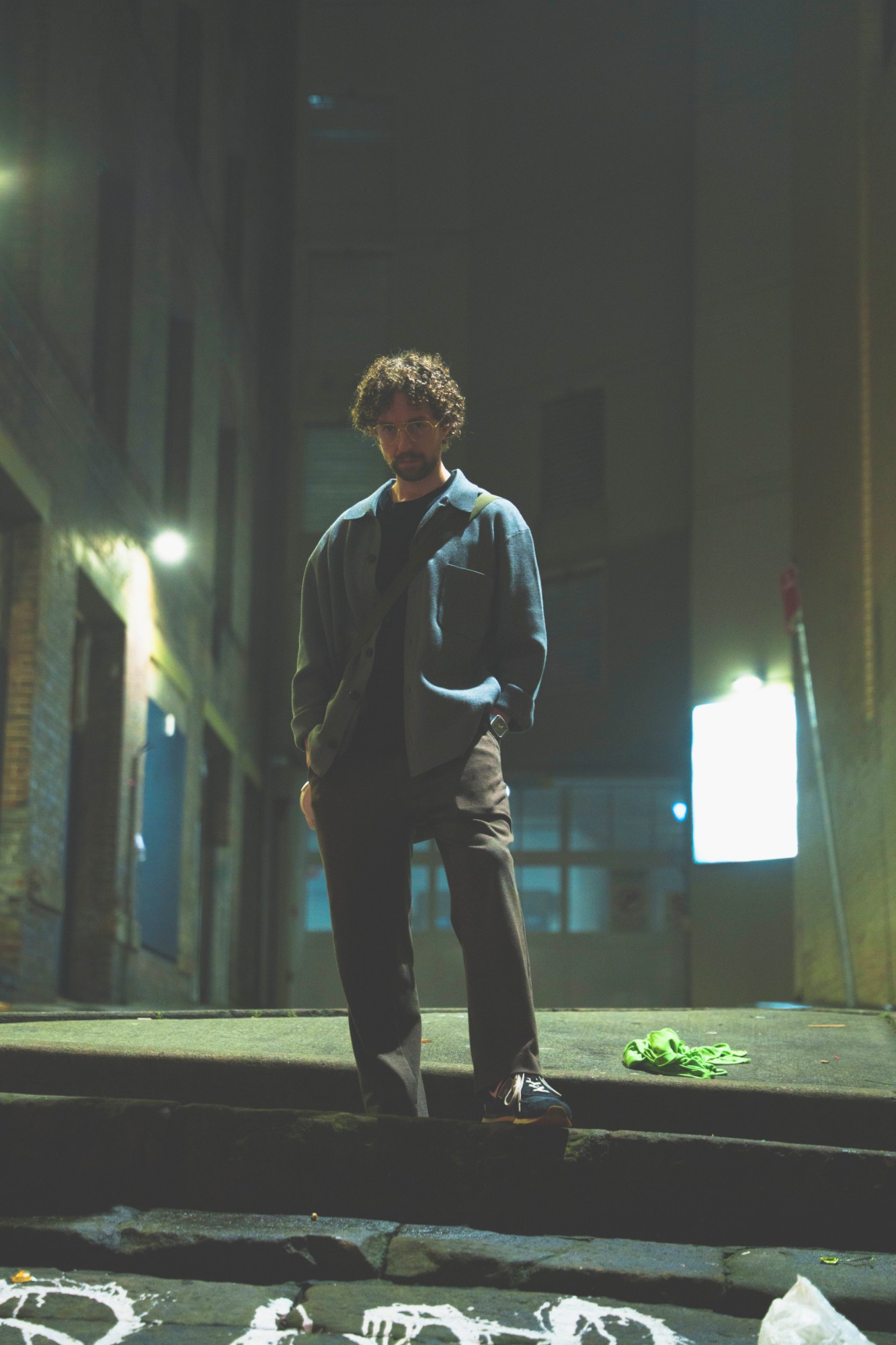 Voix Nulle standing on stone steps in a laneway at night